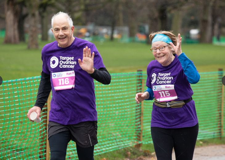 A man and a woman running, wearing Target Ovarian Cancer t shirts and race numbers.