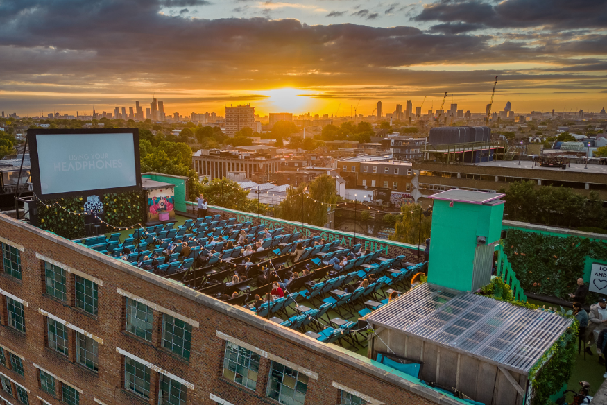 Open air cinema in London: A cinema on the roof of the Bussey Building in Peckham at sunset, with the central London skyline visible in the distance.