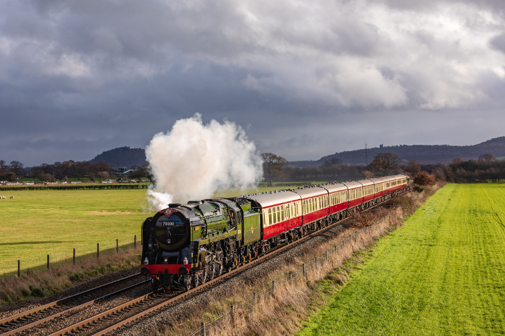 A green steam train chuffing through the open countryside