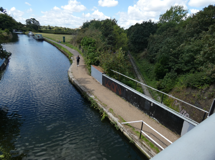 Photo taken from the road bridge over the canal - the canal is directly below, and the railway emerges beneath it, to the right.