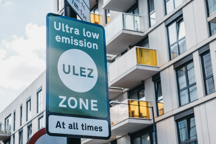 ULEZ expansion: a green and white ULEZ sign in front of a block of flats. 