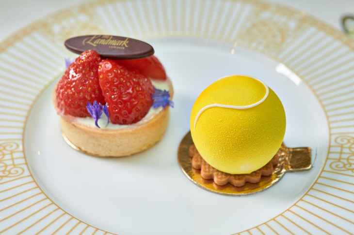 A plate with two desserts on: a strawberry tart, and the mousse shotrbread designed to resemble a tennis ball. 